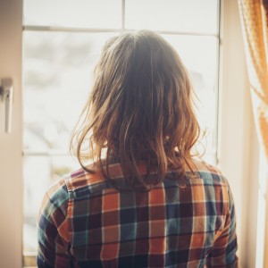 Woman looking out window at home