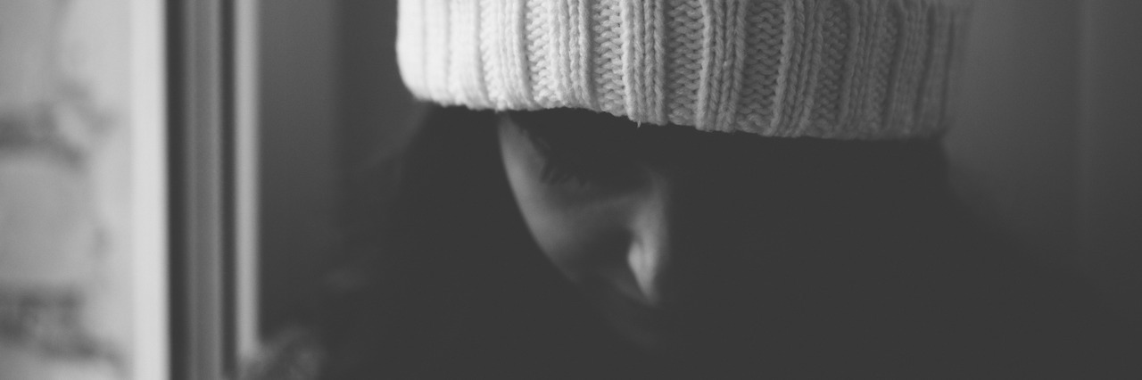 Dealing With Trauma, Depression and Anxiety at Christmas Young woman in a cap longs near a window. Black and white photo close up.