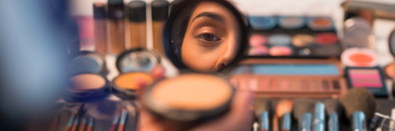 Woman looking in compact mirror before doing make-up
