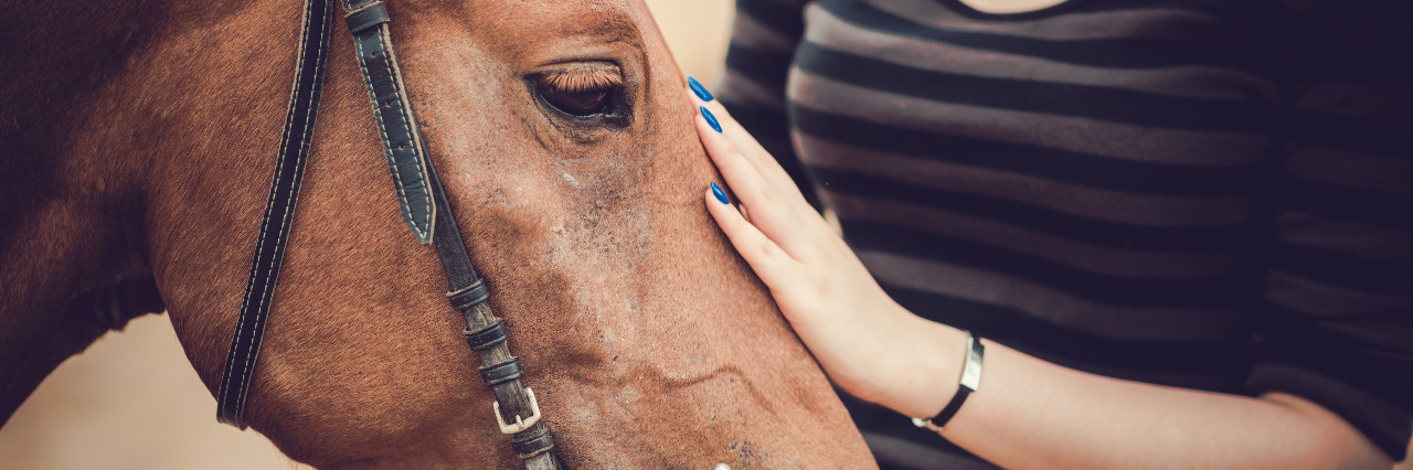 Tips for Living With Interstitial Cystitis Woman petting a horse.