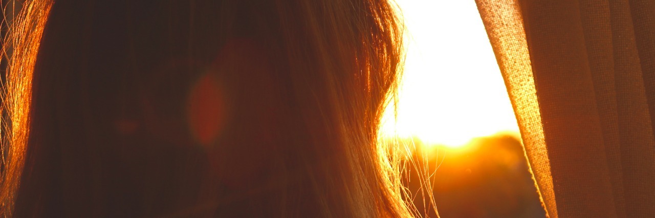 Woman at sunset looking out window