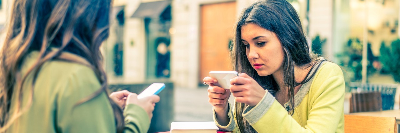 Why It Meant So Much When My Friends Said They Googled 'Spoonie' two women sitting at table looking at their phones