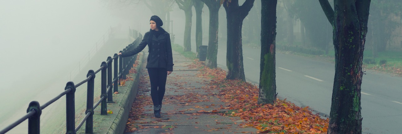 beautiful girl walking alone on misty autumn day