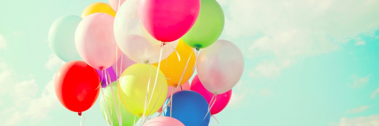 Colorful balloons against a blue sky with clouds