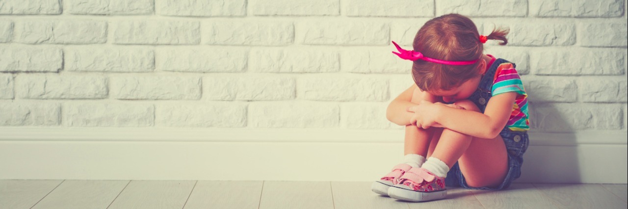 What It's Like to Have a Lifetime of Anxiety and Depression little child girl crying and sad about an empty brick wall