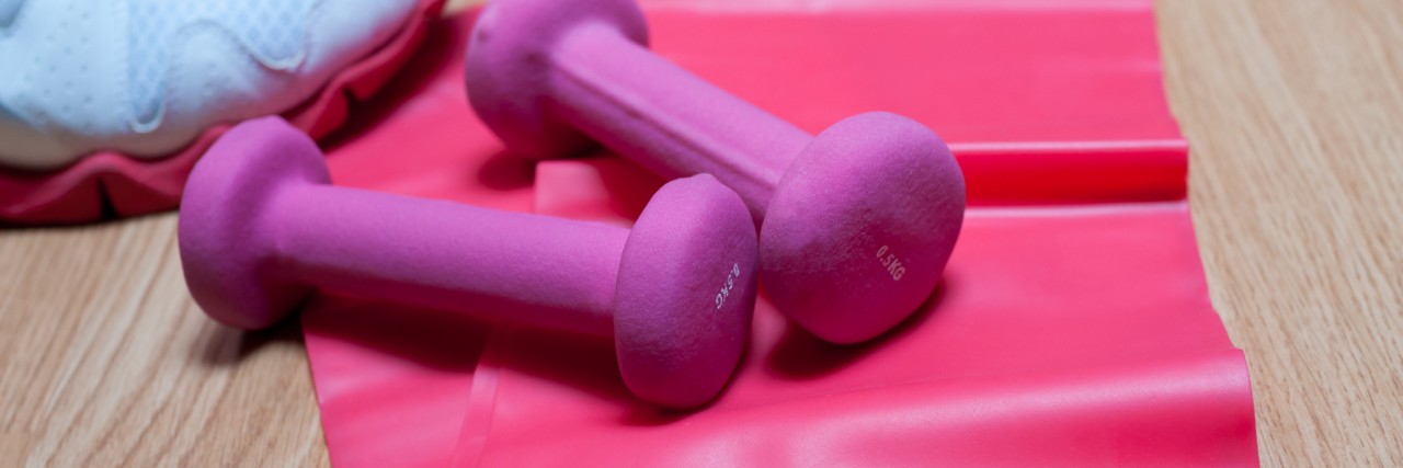 Exercise equipment. Sneakers, dumbbells and resistance band.