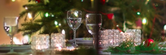 Christmas tree and table set with glasses from the perspective of outside the window