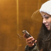 Young adult female spends time with her smartphone on bus