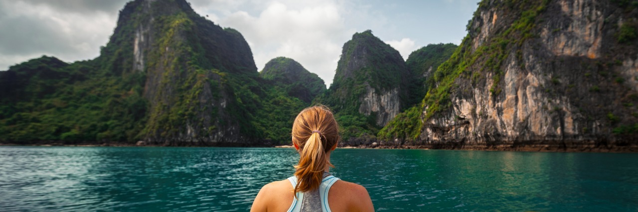 How To Travel Abroad With Fibromyalgia and IBS woman kayaking in a tropical bay surrounded by mountains