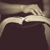 close up of man holding a bible in his hands and turning the page
