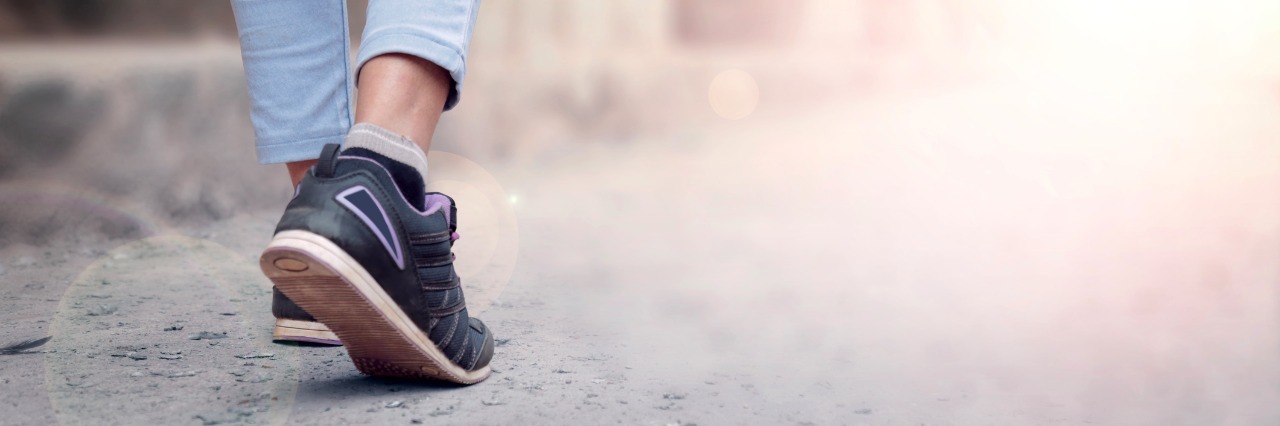 Why I'm Not Setting a New Year's Resolution to Get 'Better' This Year woman jeans and sneaker shoes walking down road