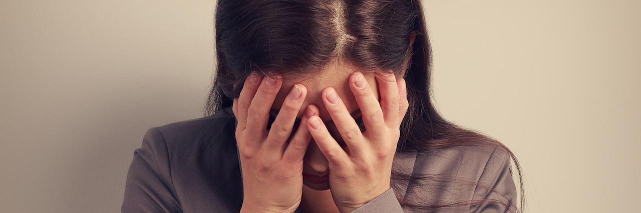 Business unhappy depression woman in suit covering the hand the face. It is fail. Toned portrait