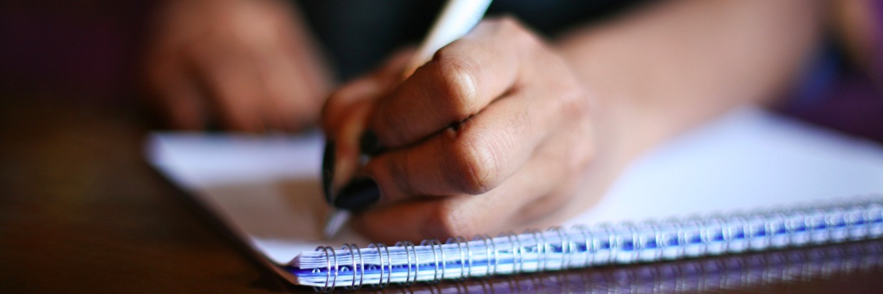 Woman writing in notebook on table