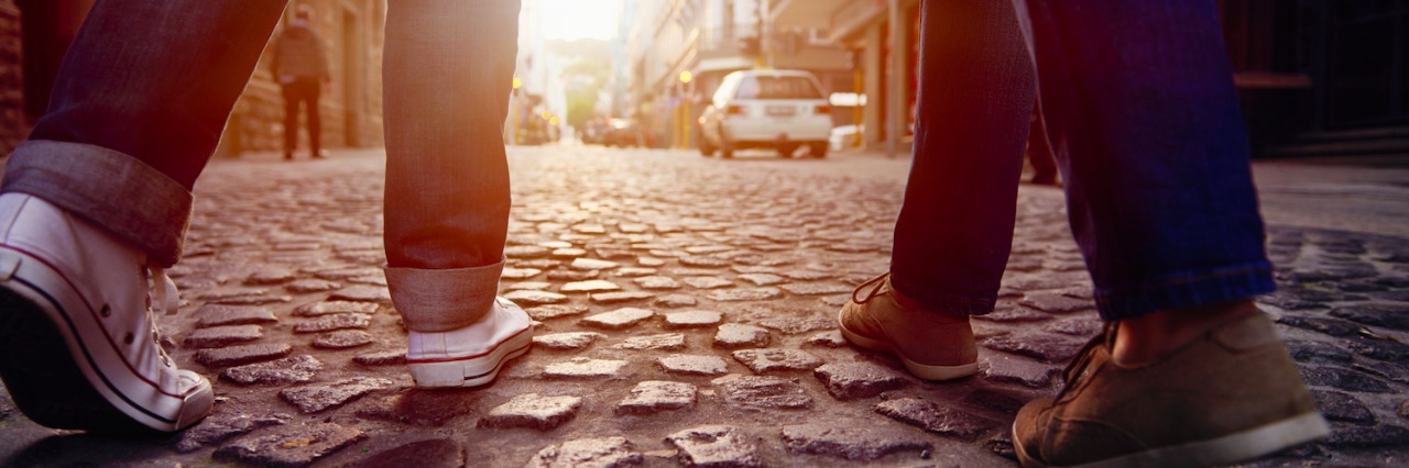 Two people walking on cobblestone street