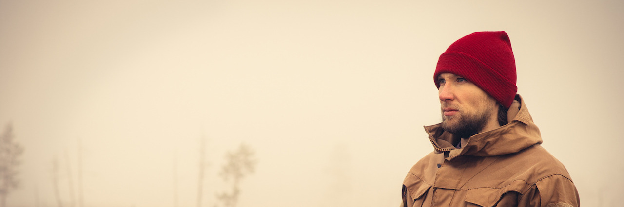 When You Are Dealing With the Loss of a Loved One at Christmas Young Man wearing winter hat clothing outdoor with foggy nature on background Travel Lifestyle and melancholy emotions concept film effects colors