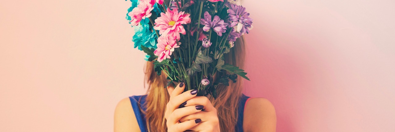 woman holding a bouquet of flowers in front of her face