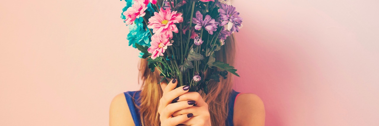 How I Realized Bipolar Disorder Wasn't My Entire Identity woman holding a bouquet of flowers in front of her face