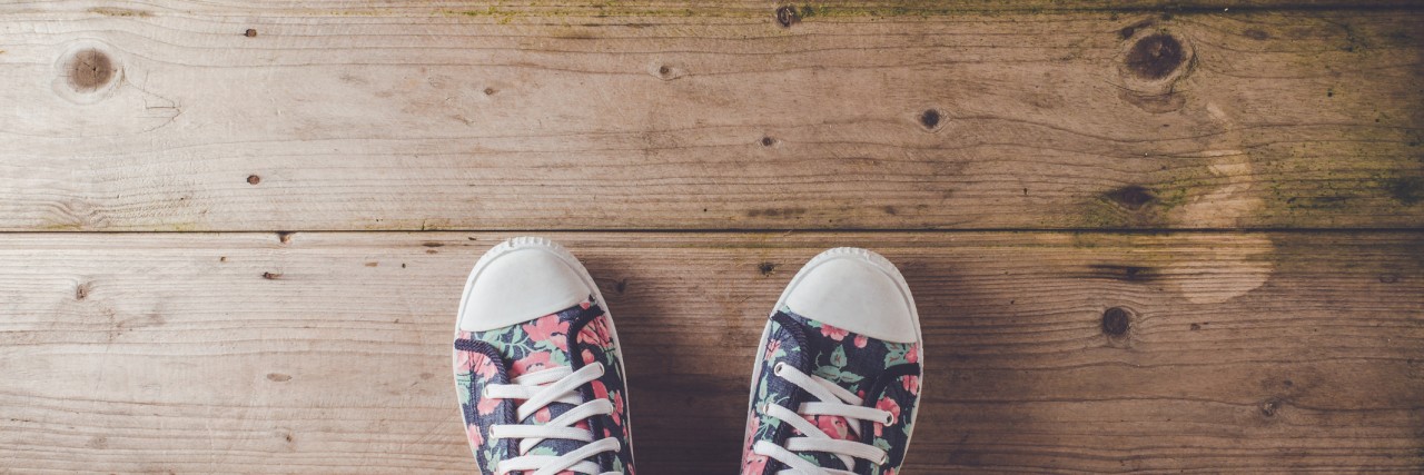 Female sneakers with floral pattern standing on wooden floor