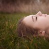 teenage girl lying on grass with her eyes closed