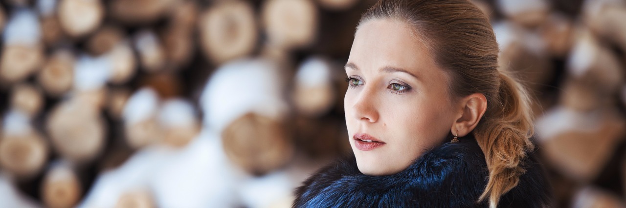 Christmastime With Depression Winter portrait of blonde woman on firewood background