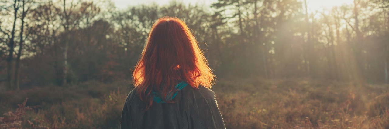 Woman Writes Letter to Herself Before She Knew About Her Autism young woman standing in forest at sunset