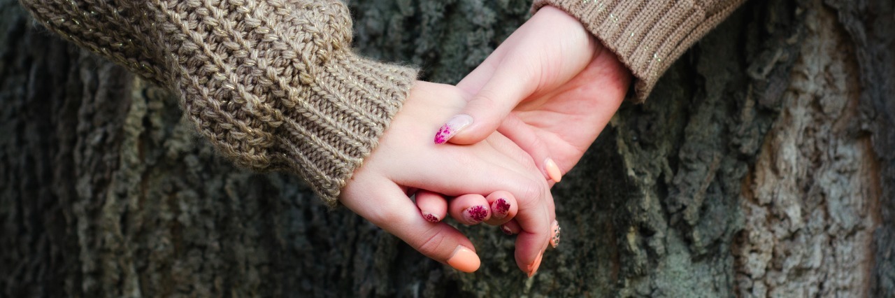 Anxiety Disorders and Friendships girls holding hands against tree bark in autumn