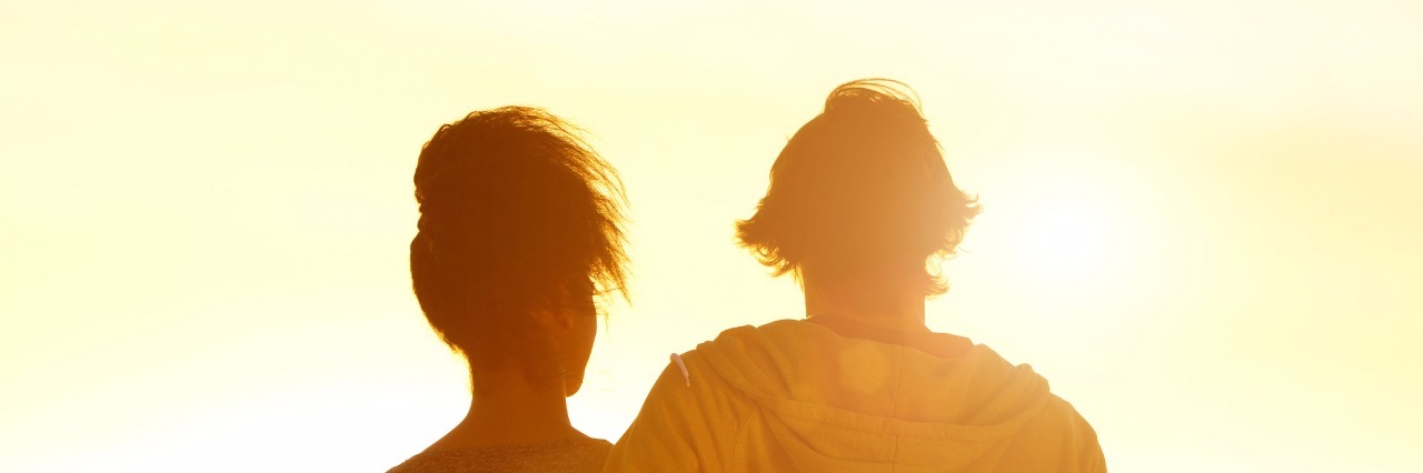 Young couple embracing looking at sunset