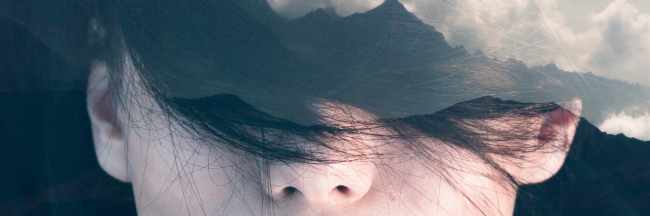 Double exposure portrait of young woman combined with photograph of mountainious landscape shot from a plane