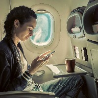 Woman sitting at airplane and looking at mobile phone.