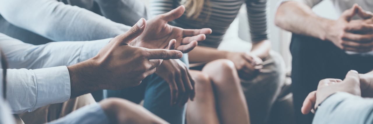 Close-up of people communicating while sitting in circle and gesturing