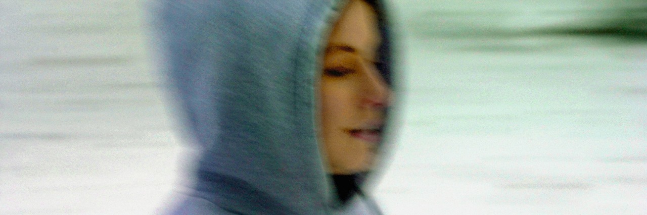 The Invisible Scars of Postpartum Depression Side profile of a young woman wearing hooded shirt