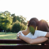 Closeup of mom and daughter embracing on a park bench