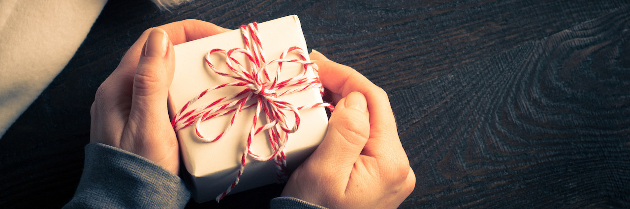 10 Holiday Gifts for the PTSD Spouses and Partners Woman holds Christmas gift in his hands at wooden table. Image toned. Copy space.