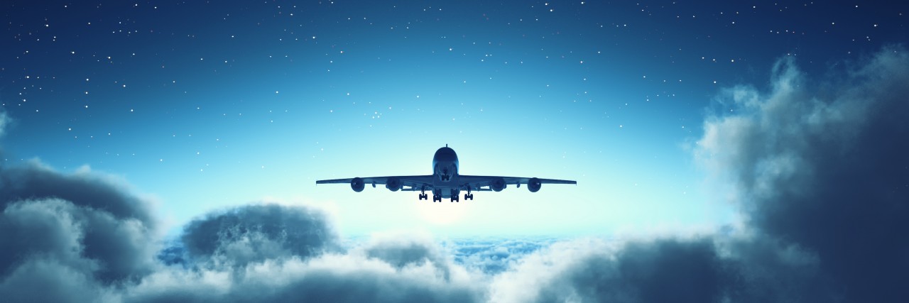 Why Air Travel Is Often Inaccessible to Wheelchair Users Airplane flying over cloudy sky.