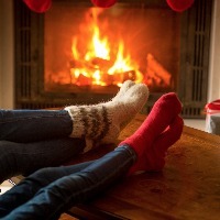a couple wearing festive woolen socks relaxes in front of the fireplace and their christmas stockings