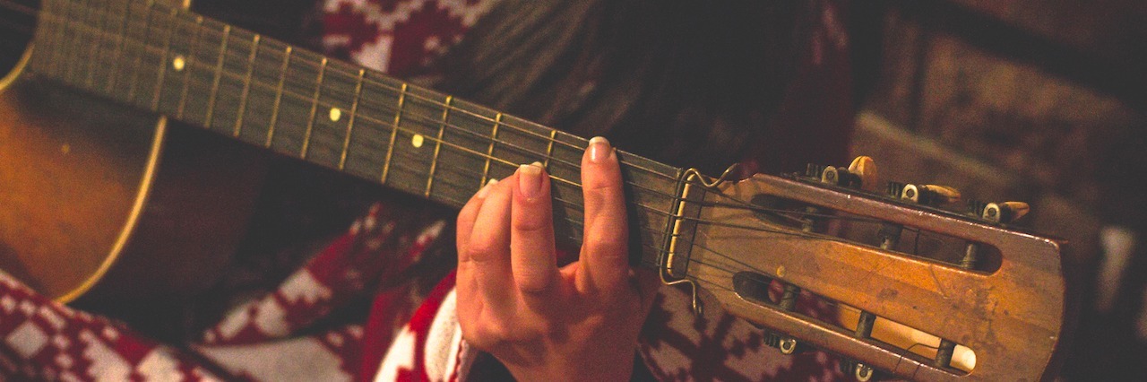 Why a Guitar Is a Great Gift for Someone With Anxiety and Depression woman playing the guitar