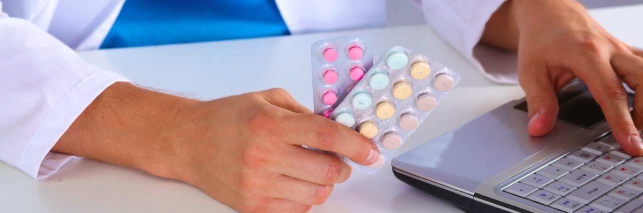 To the Pharmacist Who Judged Me While I Was Having a Migraine medicine doctor hands hold jar of pills and type something on laptop computer keyboard