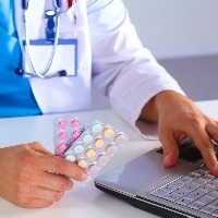 medicine doctor hands hold jar of pills and type something on laptop computer keyboard