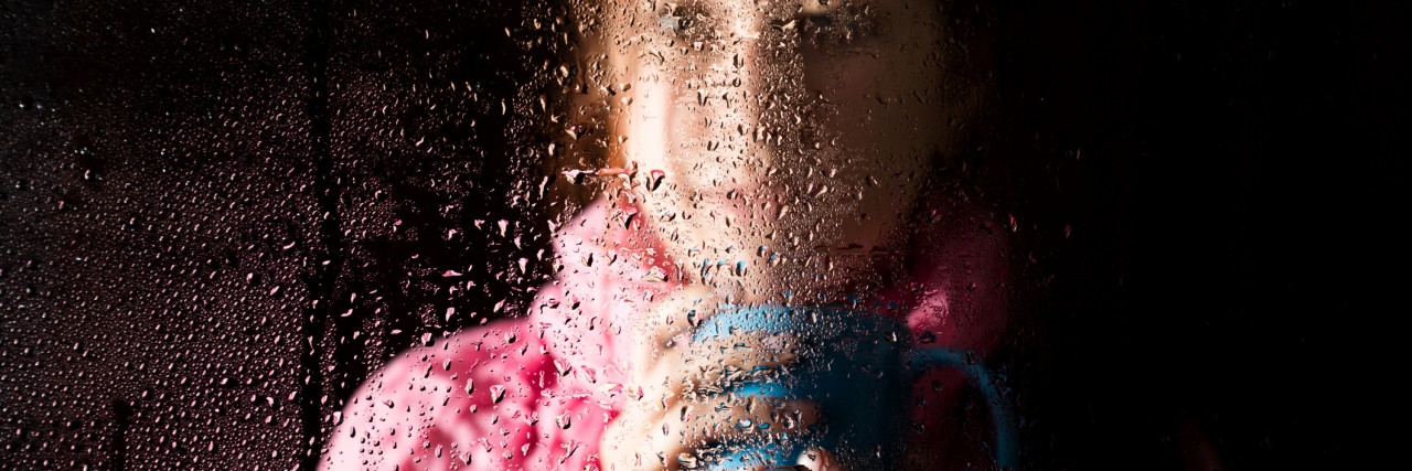 young sad woman portrait behind the window in the rain