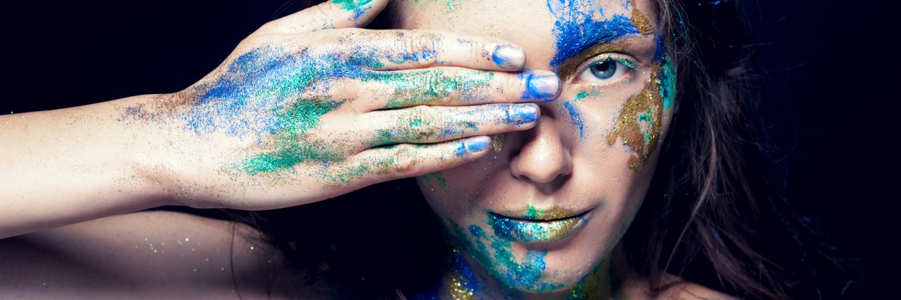 It's OK to Be the 'Same You' in the New Year Beautiful face with colored paint on a black background