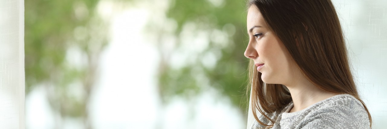 The War on Medical Marijuana: A Crohn's Patient's Response Profile portrait of a longing woman looking outdoors through a window at home or hotel room with a green background