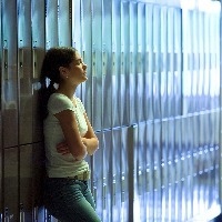 teenage girl leaning against lockers with her arms crossed at high school