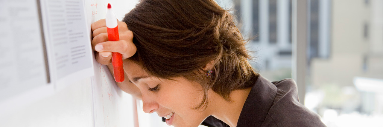 How Nonverbal Learning Disabilities Have Affected My Life Woman with marker leaning head against wall.