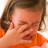 young girl crying and rubbing her eye