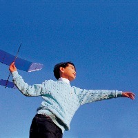 boy playing with toy plane against sky background