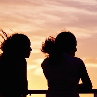 Silhouette of two women in front of a sky at sunset