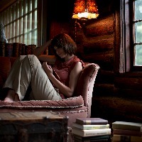 woman sitting on sofa reading book