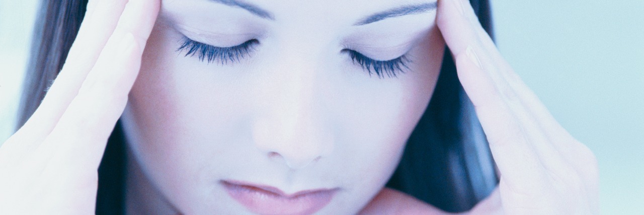 What I Wish Loved Ones Knew About My Meltdowns and Shutdowns close-up of a woman rubbing her temples with eyes closed