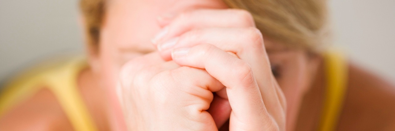 The Ups and Downs of Depression A stressed woman with her forehead leaning against her closed hands