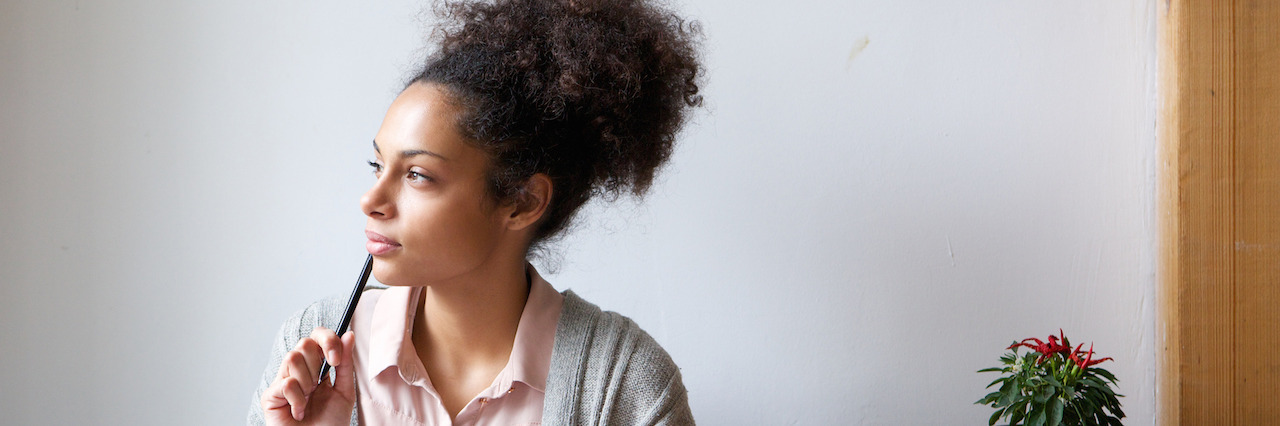 4 Tips When Depression and Anxiety Make It Hard to Write Portrait of a young woman sitting at home with pen and paper